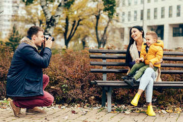 Young father photographing his son and wife in the park