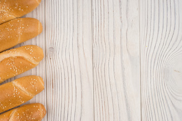 Bun with sesame seeds on old white wooden table.