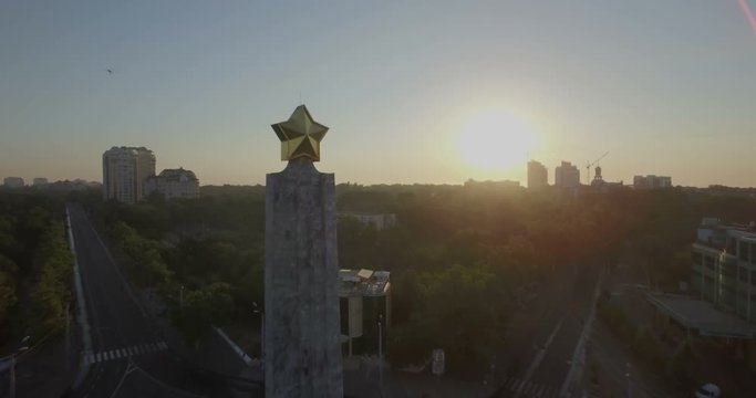Aerial camera pulls back from the star on top of the Wings of Victory monument in the Arcadia district of Odessa Ukraine as the sun rises behind