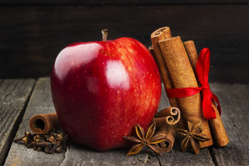 Apple, cinnamon, anisetree on a dark wooden background. Toning