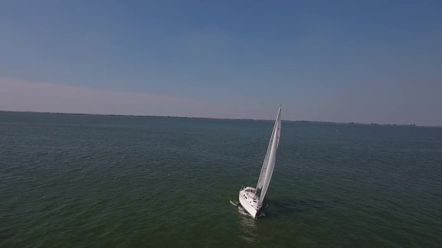 Sailboat at open sea, aerial leading shot.