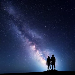 Fotobehang Milky Way with people on the mountain. Landscape with night sky with stars and silhouette of standing  man and woman. Milky way with couple. Travelers against beautiful galaxy. Universe © den-belitsky