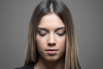 Fototapeta premium Moody portrait of beauty with perfect skin looking down over gray studio background
