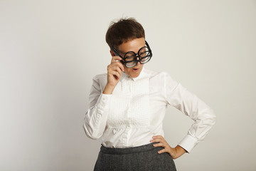 Funny teacher in three pairs of round black glasses thinking about something
