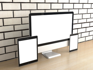 Responsive computer devices on desk, isolated blank screen for mockup design advertising. PC display, tablet, mini or smartphone on table loft office. White brick wall background. 3d rendering