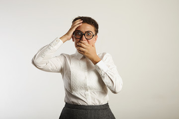 Fearful emotional young woman covers her mouth in horror isolated on white