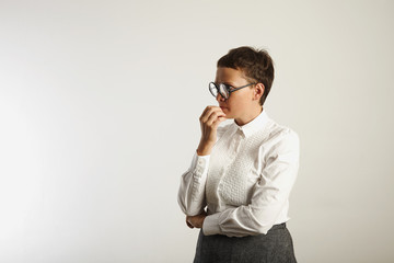 Teacher in conservative white and grey outfit and round black glasses deep in thought isolated on...