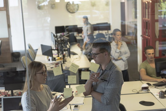 young couple at modern office interior writing notes on stickers