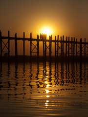 U Bein Bridge at sunset with people crossing Ayeyarwady River, M