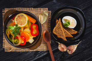 Fresh vegetable soup in a pot on black background