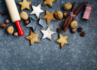 Christmas cookies, roller pin, cinnmoa, nuts and cookie cutter on dark background