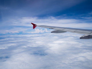 Obraz premium Airplane wing over white cloud and blue sky view from window of airplane while flying over Thailand.