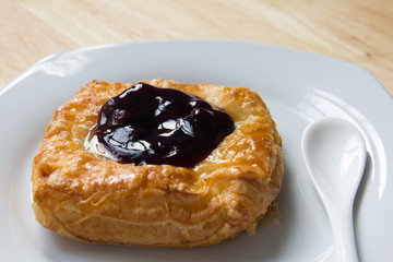Danish blueberry pie with spoon in white plate on wooden table