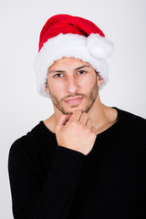 charmanter, junger Mann mit Dreitagebart und Weihnachtsm&uuml;tze zeigt Weihnachts-Emotionen