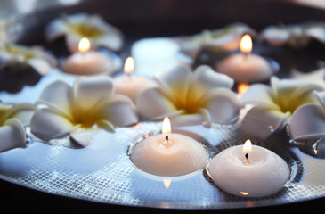 Exotic flowers and candles in bowl with water