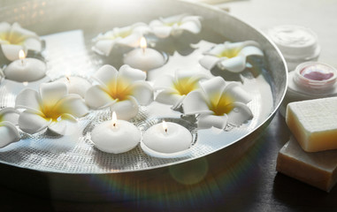 Exotic flowers and candles in bowl with water