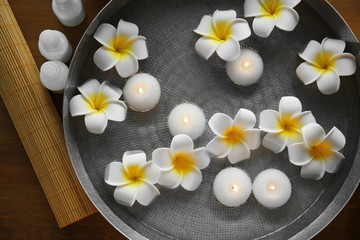 Exotic flowers and candles in bowl with water