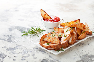 Roasted potato wedges with rosemary and tomato sauce, selective focus
