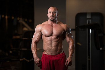 Obraz na płótnie Canvas Fitness Shaped Muscle Man Posing In Dark Gym