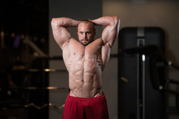 Fototapeta na wymiar Muscular Man Flexing Muscles In Gym