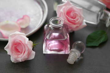 Essential oil with roses on color background