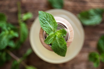 Essential oil with mint on wooden background