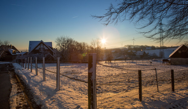kleine Winter Farm mit Tier und Schneedecke vor blauem Himmel und Gegenlicht