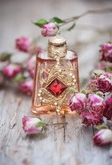 Obraz na płótnie Canvas Dry roses and vintage perfume bottle on old wood background