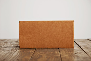Craft blank cardboard package box presented on stressed brushed wooden table, isolated on white background