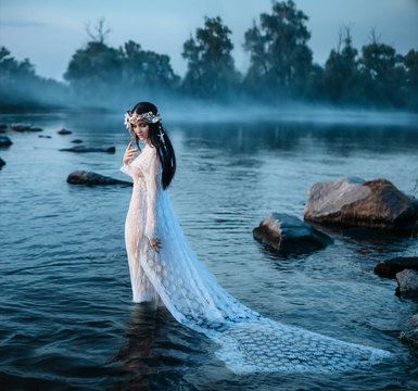 Luxurious lady in sexy, white dress walks into the water