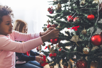 African little girl decorating the Christmas tree. Natural light.