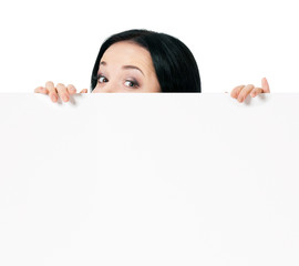 Fototapeta premium Surprised woman eyes over blank promotional display, isolated on white background. Businesswoman looking over top of white sign. Advertisement business concept - female with white blank board.