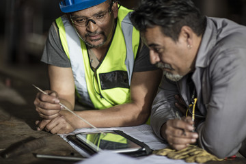 Engineers discussing construction plans on digital tablet