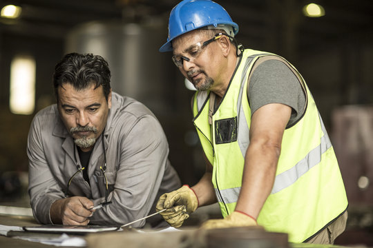 Engineers discussing construction plans on digital tablet - Powered by Adobe