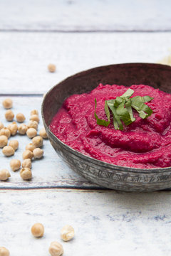 Bowl of beetroot hummus an chick-peas on wood