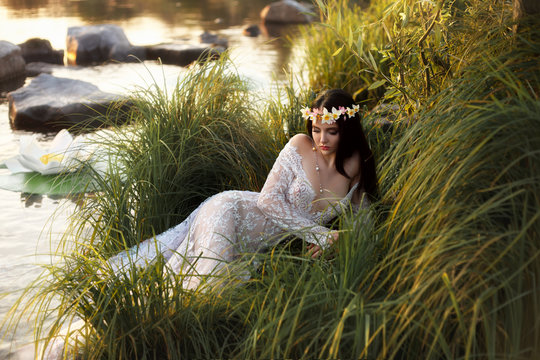 Luxurious, sexy lady, in elegant long dress lying on grass