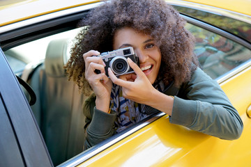 Cheerful girl taking pictures from a yellow cab, New York City