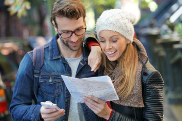 Trendy couple using smartphone and city map of New York on their journey