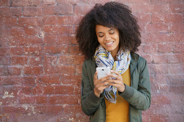 Beautiful trendy mixed raced girl using smartphone in the street