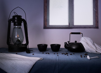 kerosene lamp and glasses with black tea on a table in the evening   background of  window