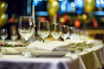 Fototapeta na wymiar Glasses, forks, knives, napkins and decorative flower on a table served for dinner in cozy restaurant.