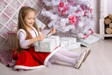 Girl in Christmas dress opens presents.