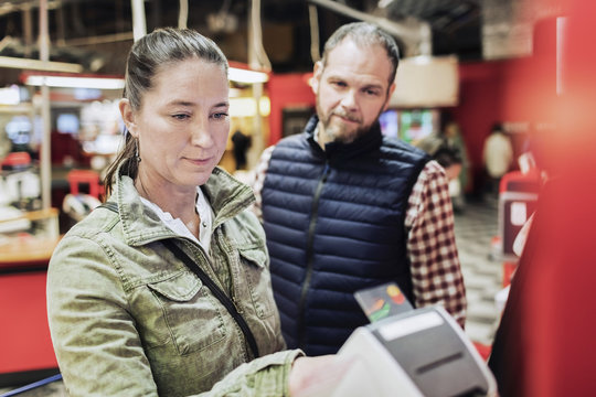 Woman doing payment while standing with man at supermarket