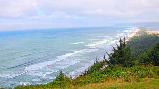 Cinematic, sliding shot of iconic Ocean shore in Oregon by Pacific Coast Highway, scenic landscape. Spectacular coastal vista views of distant breaking waves, misty forests, sea mounts and mountain