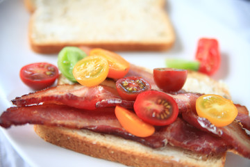 Fototapeta na wymiar Cherry tomatoes on thick-cut bacon sandwich 