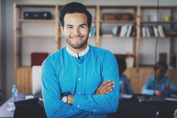 Portrait of successful confident hispanic businessman smiling at the camera in modern office.Horizontal,blurred background .