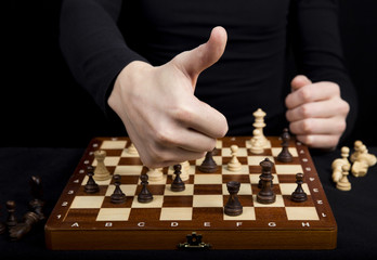 close-up of a girl holding her hands over a wooden chess board,