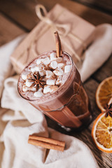 Cocoa or latte or hot chocolate with marshmallow and flavored with cinnamon. On a brown wooden background. Christmas present. Christmas concept. Christmas holiday.