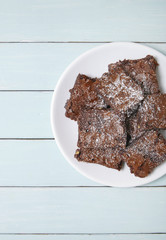 A plate full of freshly baked chocolate fudge brownies on a blue wooden kitchen table background