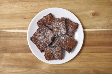 A plate full of freshly baked chocolate fudge brownies on a wooden counter top background